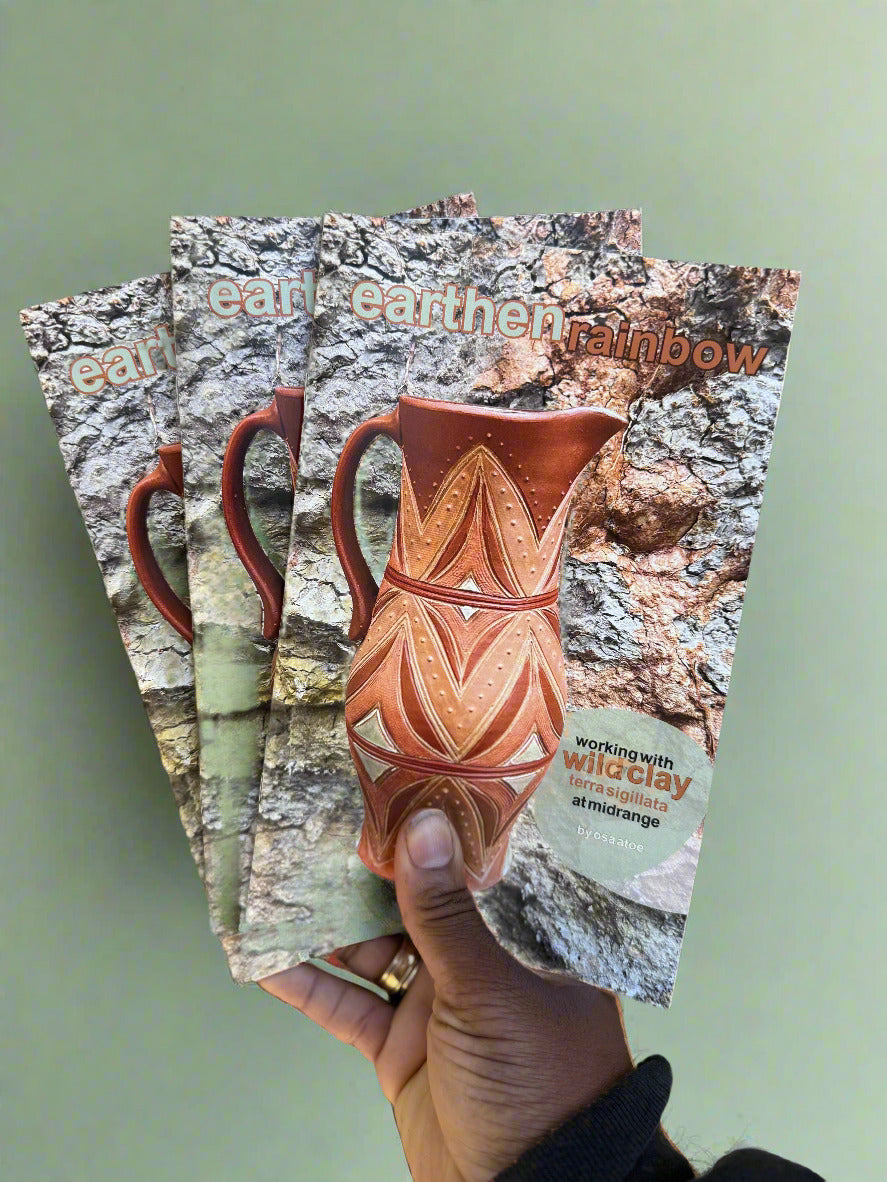 my hand holding three copies of earthen rainbow zine